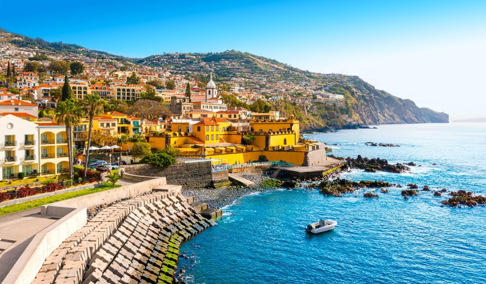 A rocky coastline with yellow buildings and deep blue sea