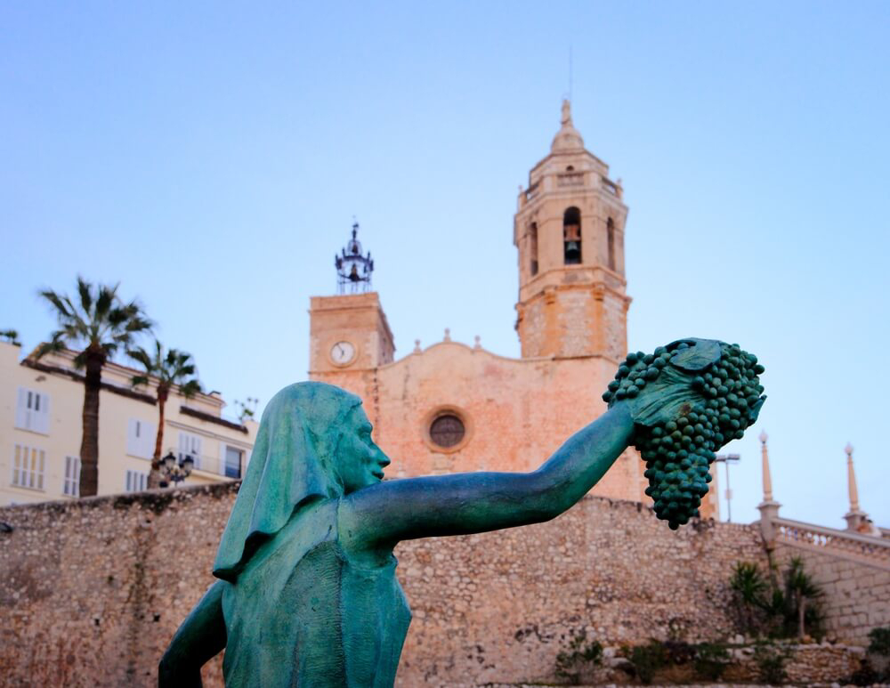 Cava tours in Barcelona: A bronze statue of a woman and a bunch of grapes