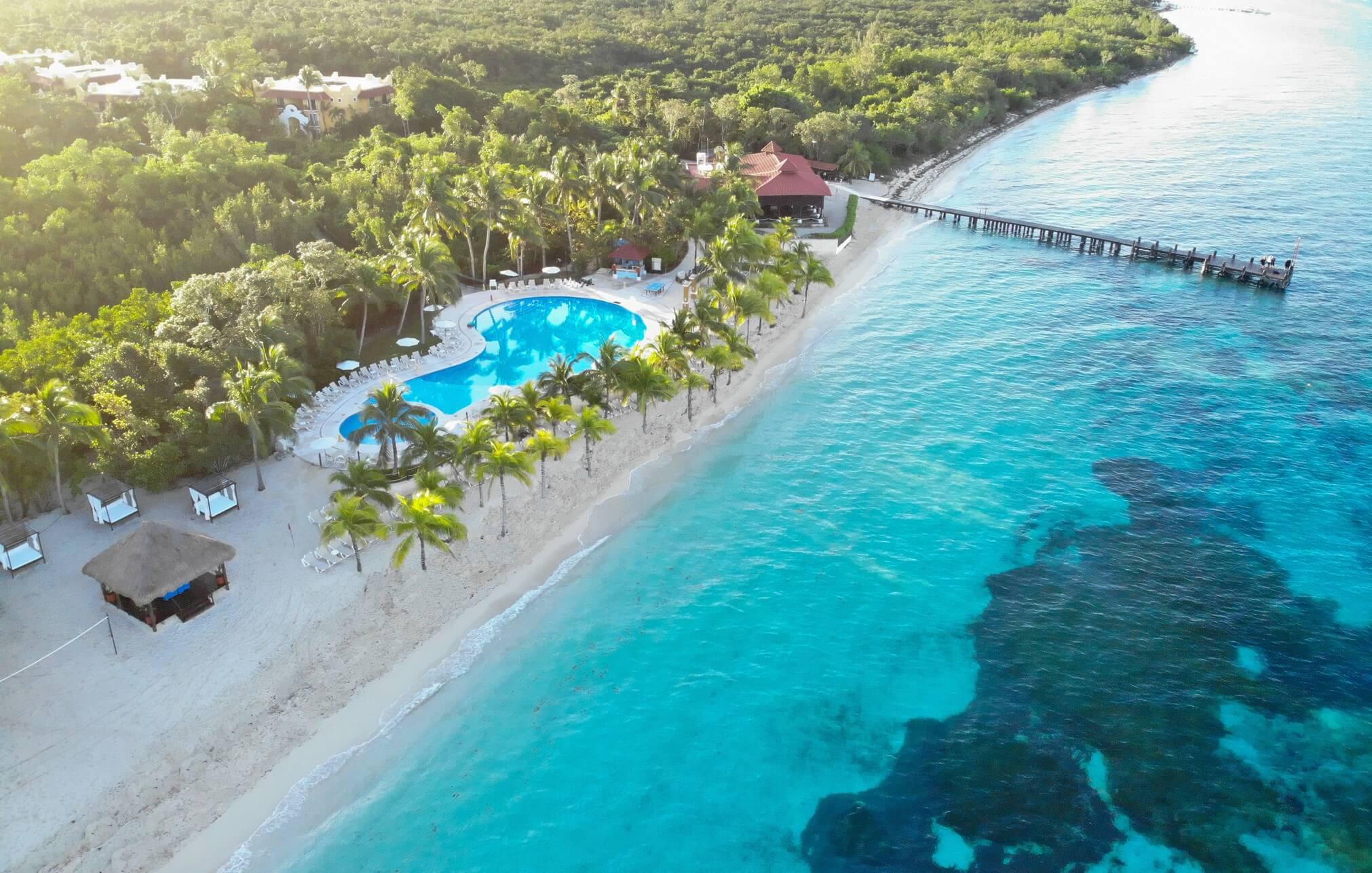 Cozumel: A white sand beach from above with a swimming pool and promenade