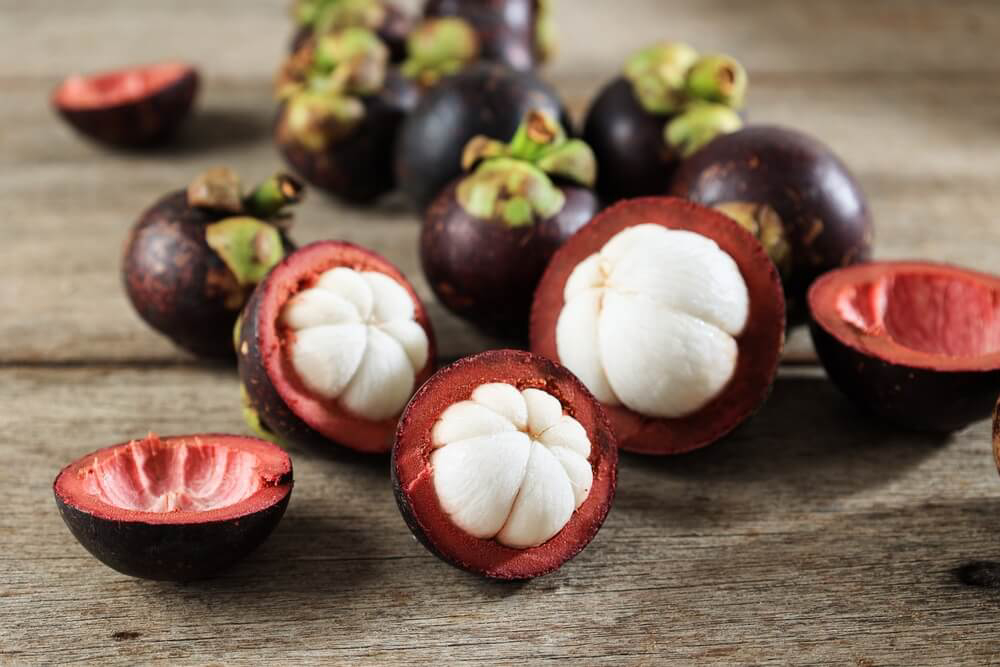 Mangosteen: A wooden table with mangosteen fruit cut open on top