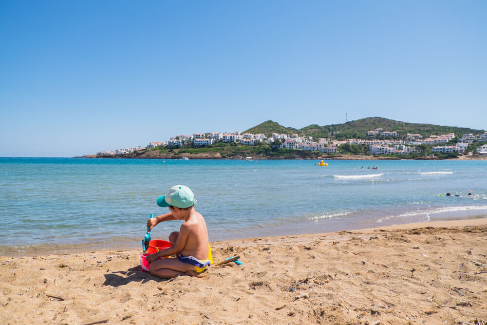 Kind spielt am Strand von Cala Tirant in Fornells auf Menorca.