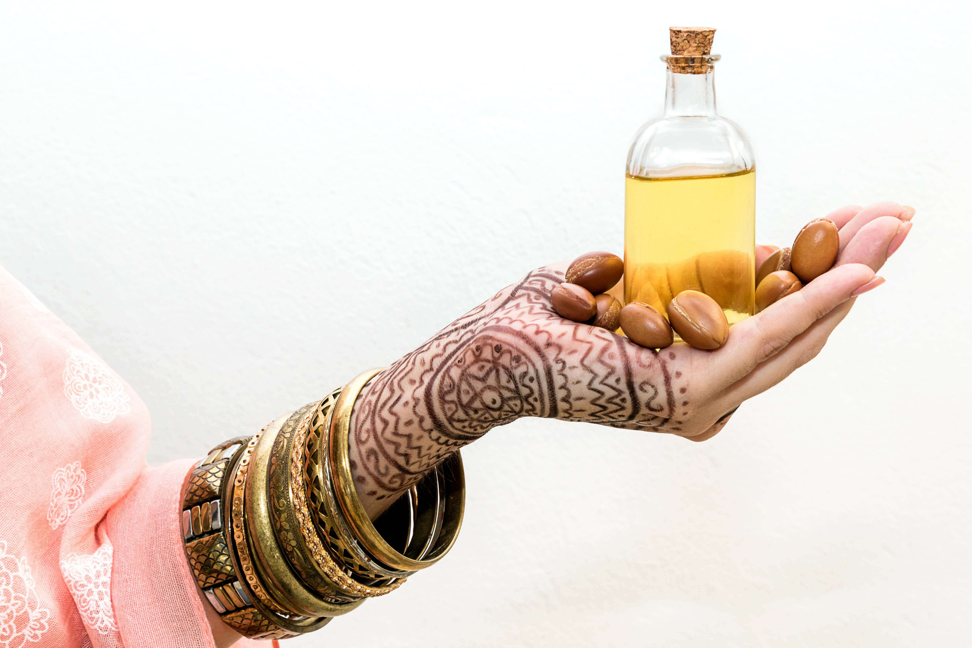 Moroccan beauty products: Henna tattooed hand holding a bottle of argan oil