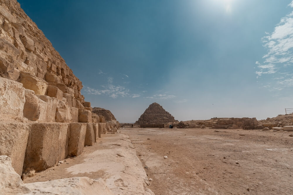 Pyramids of Giza facts: A limestone brick wall and sandy floor with a pyramid in the distance