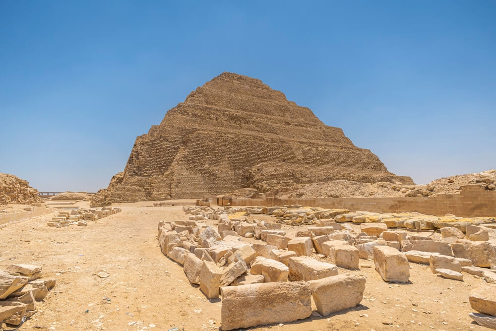 Pyramids of Giza facts: The Pyramid of Djoser in a desert with big building blocks in the foreground