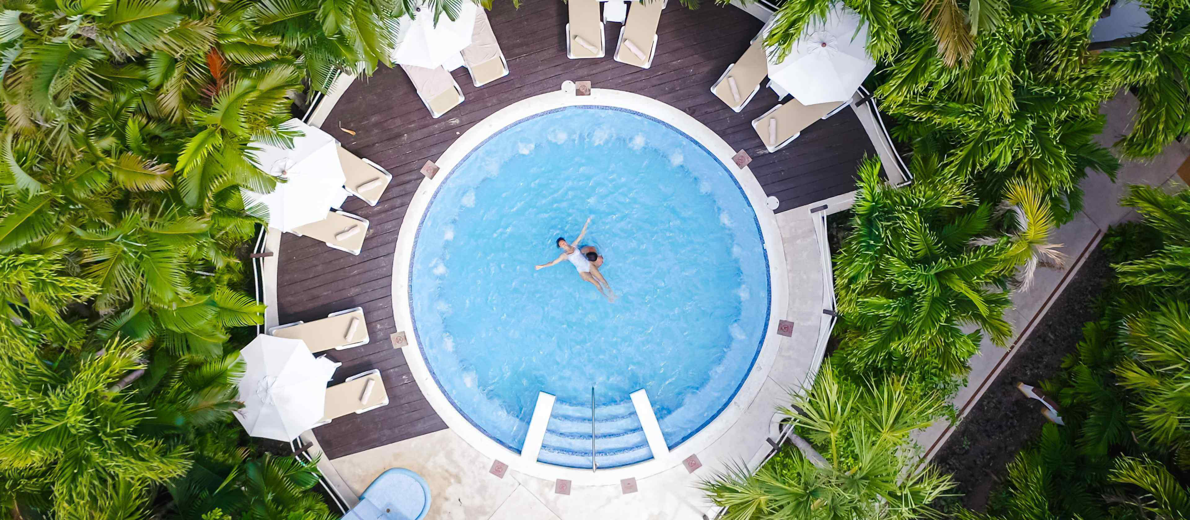 Flitterwochen-Urlaub: Paar in einem Whirlpool umgeben von tropischer Vegetation.