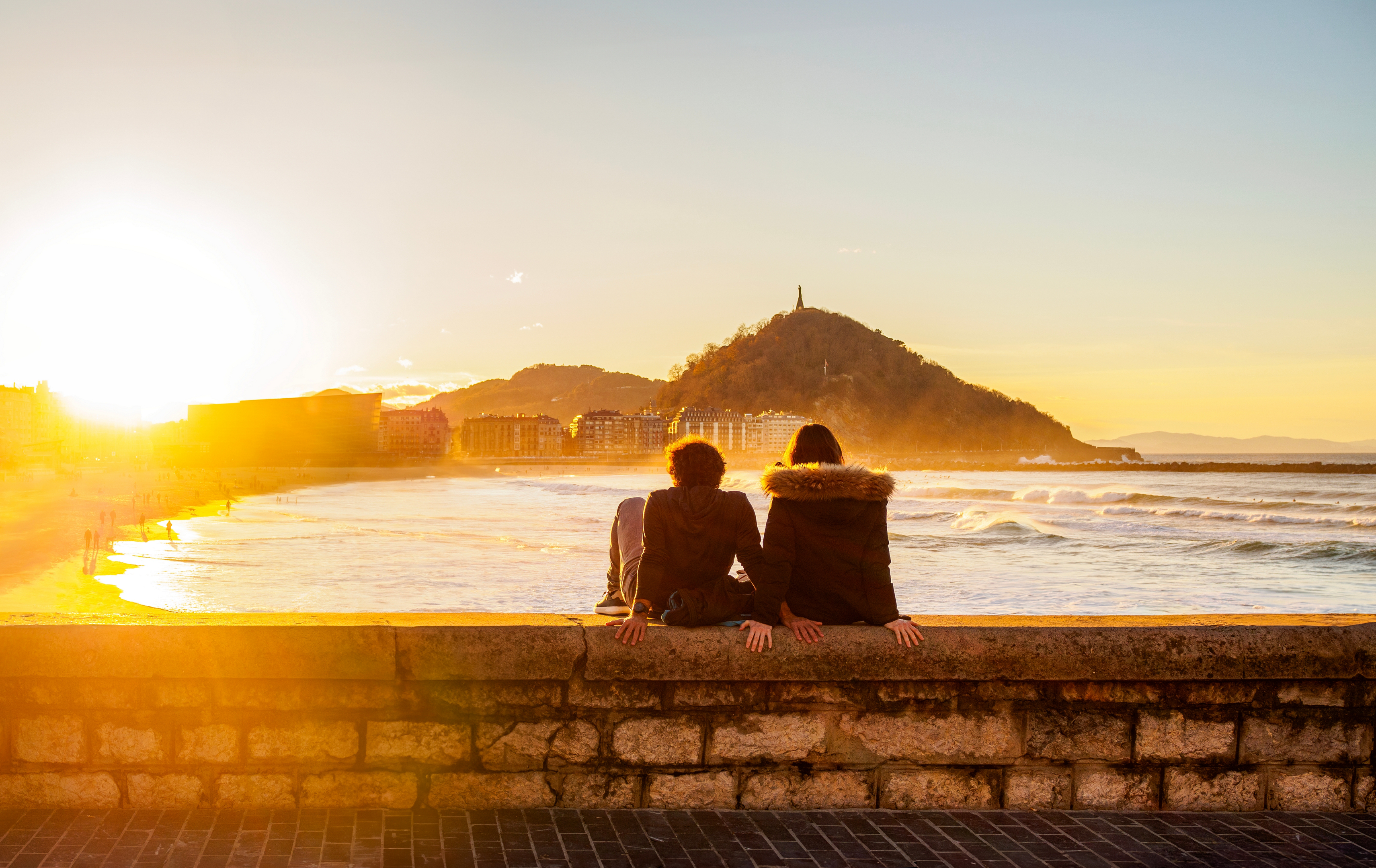 Ein Paar sitzt in der Abenddämmerung am Paseo Nuevo in San Sebastián.