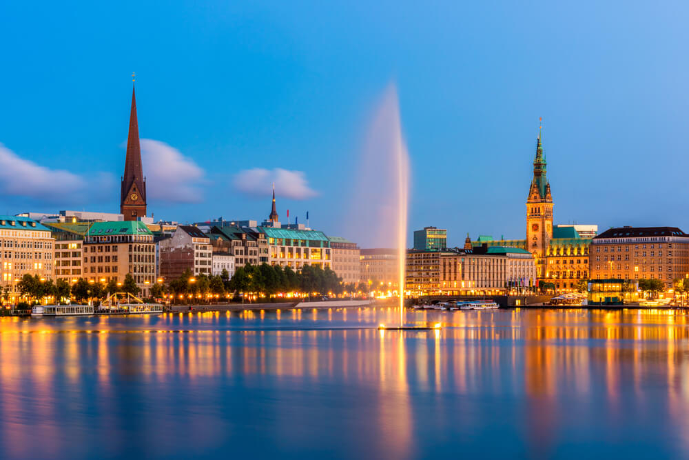 Sehenswürdigkeiten in Hamburg: Alsterfontäne auf der Binnenalster mit Jungfernstieg und Rathaus.