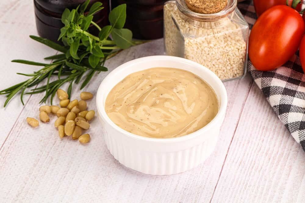 Intxaursaltsa: A ramekin with a cream liquid inside and sesame seeds in a bottle
