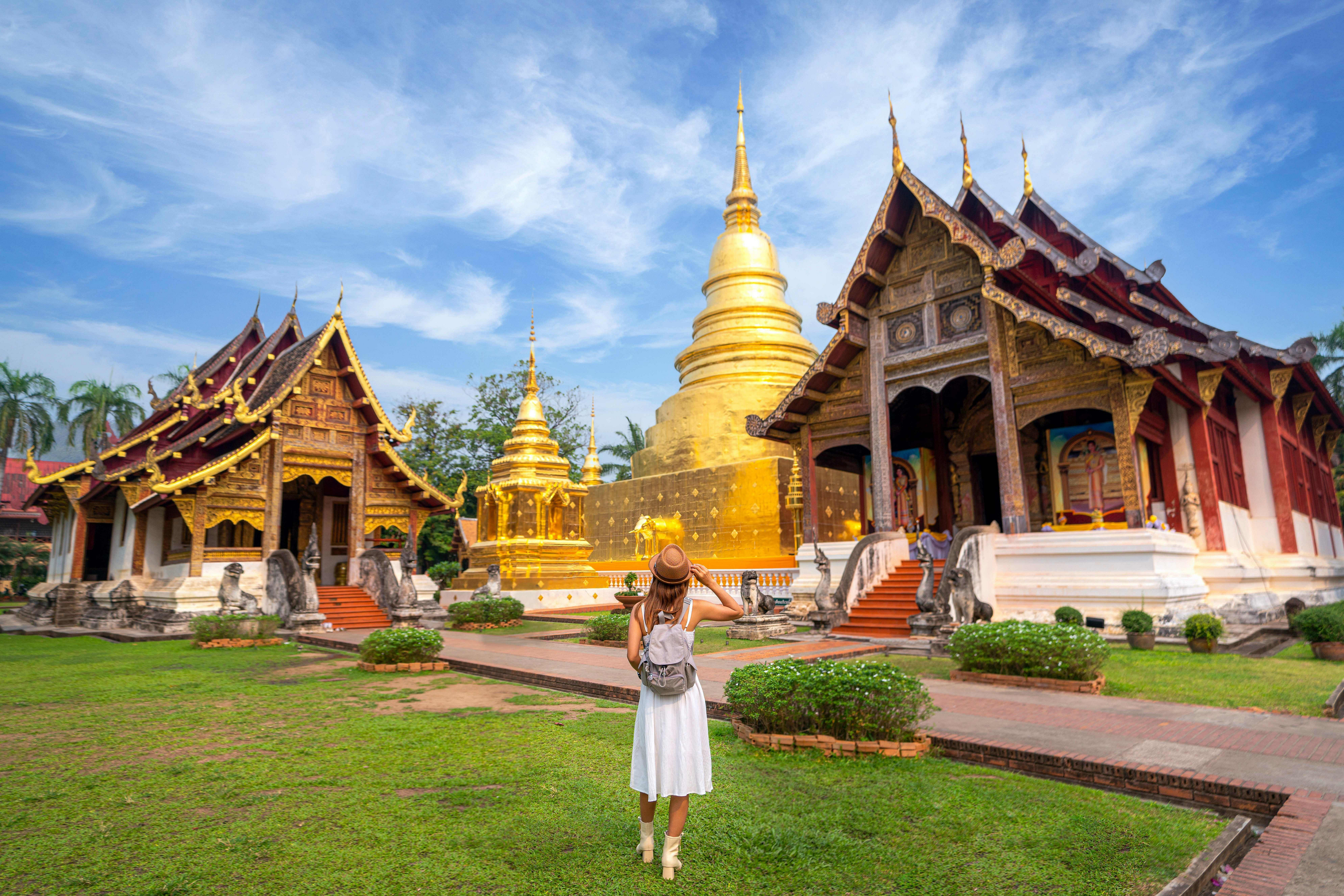 Temples in Thailand: A woman in a white dress visiting a Thai temple