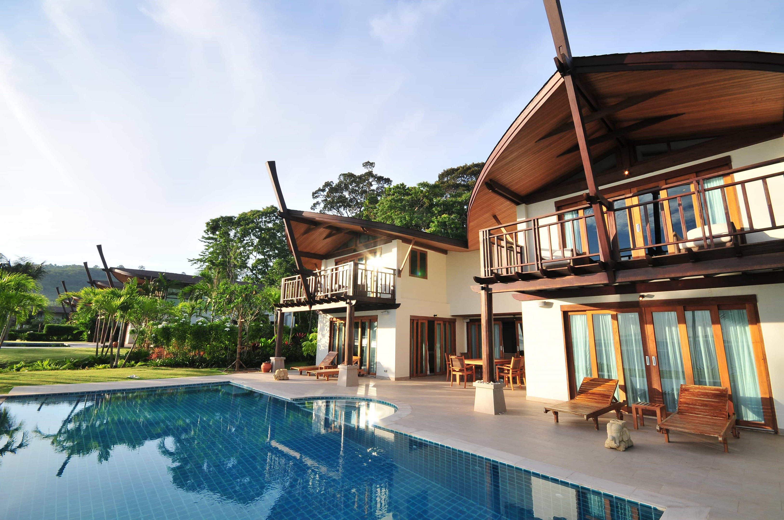 Coconut Island: A white villa with a wooden roof  in front of a large pool