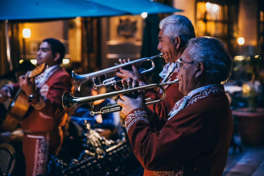 Mariachi: A group of men dressed traditionally as Mariachis playing instruments 