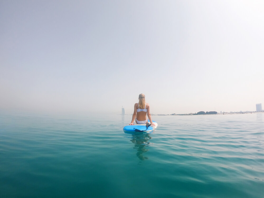 SUP Yoga: A woman sitting on a paddleboard in the middle of the sea